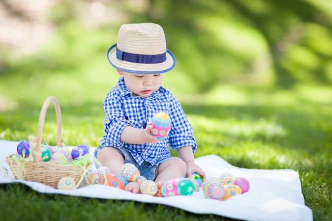 Male Child Outside Wearing Rabbit Ears Playing with Easter Eggs