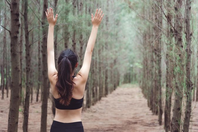 Woman stretching arms up working out in forest