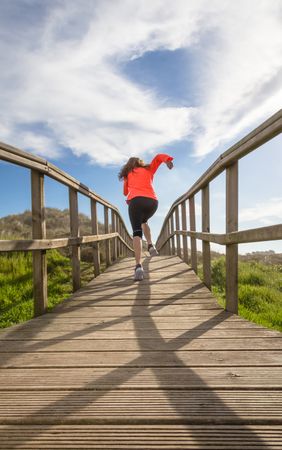 Woman sprinting down wooden path