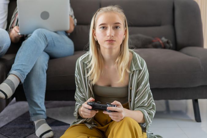 Young woman sitting on the floor controlling joystick playing video game