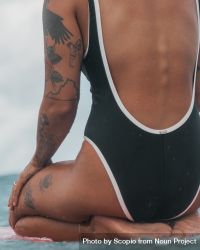 Back view of Black woman in one piece swimsuit sitting bewZp5