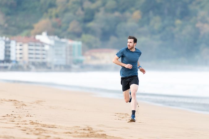 Sportsman in active wear jogging on lonely beach