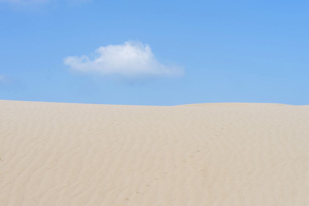 Lonely cloud over a dessert dune against blue sky