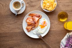 Tasty bacon and eggs with juice at table