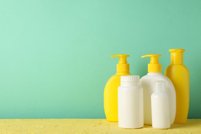 Baby hygiene accessories on yellow table against mint background