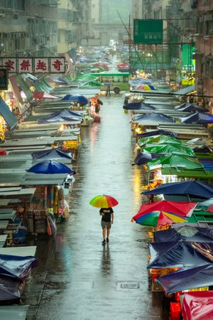 Back view of man with umbrella walking in street market