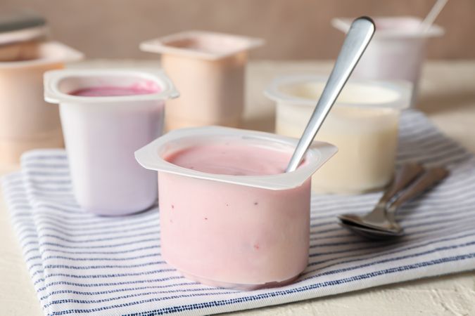 Composition with plastic cups with yogurt on table