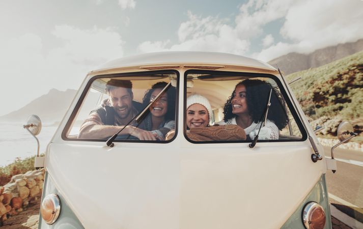 Group of friends on roadtrip smiling and laughing inside van