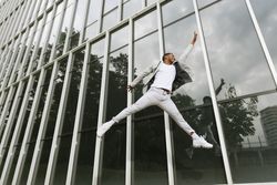 Enthusiastic Black man jumping raising hand like superhero