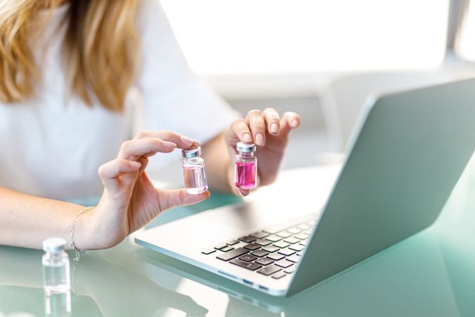 Female working at laptop with medical vials