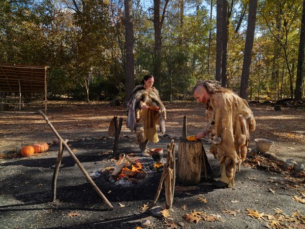 Two people reenact preparing a meal in the 1600s at  Powhatan Indian Village, Jamestown, Virginia