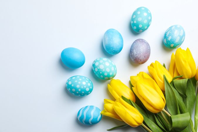 Flat lay composition with Easter eggs and flowers on neutral background, space for text