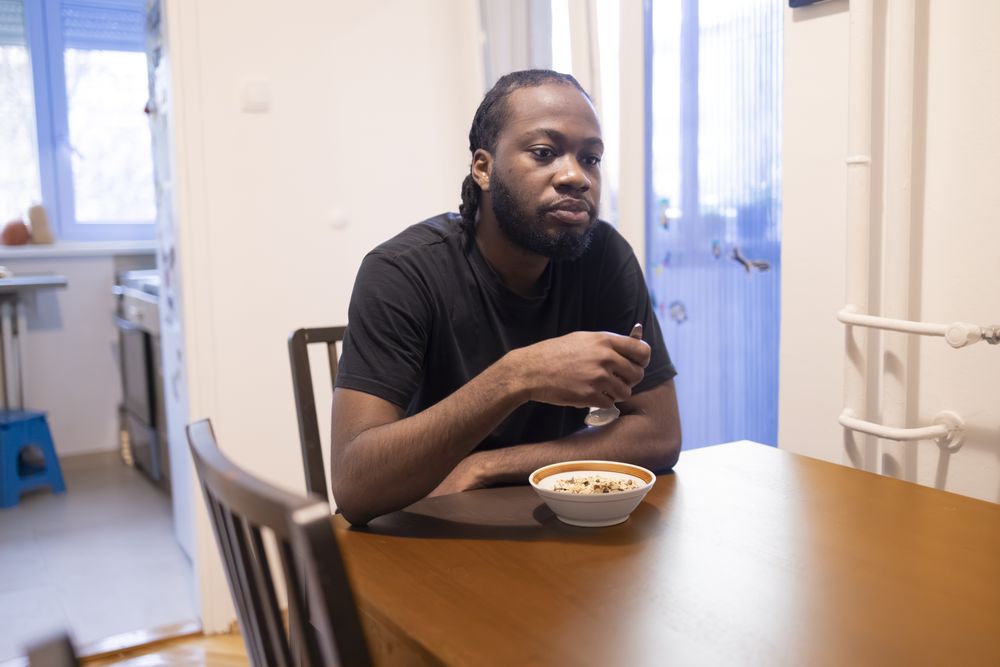 Black man Eating Breakfast at Home in Natural Light.