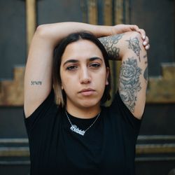 Portrait of woman raising her arms with floral tattoos on them