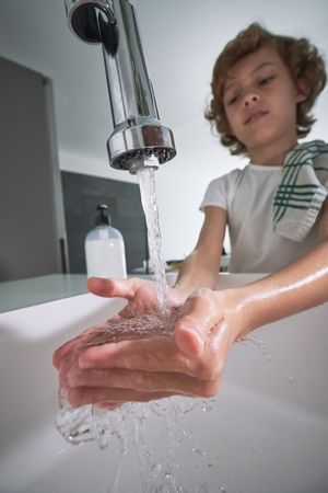 Boy washing hands in sink