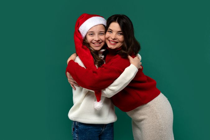 Mum and teenage daughter share a warm holiday hug, smiling