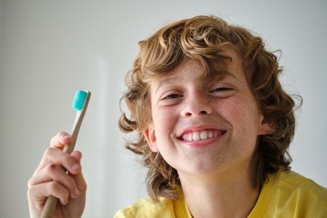 Smiling child with toothbrush on light background