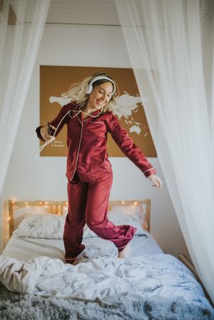 Woman with headphones dancing in bed