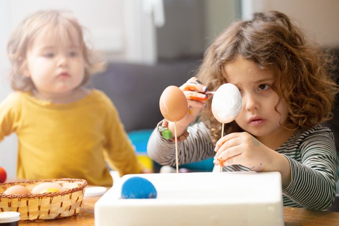 Sisters painting Easter eggs at home