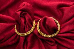 Beautiful shiny golden bangles with Indian traditional design on a red velvet background