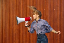 Side view of woman yelling into megaphone in checkered shirt