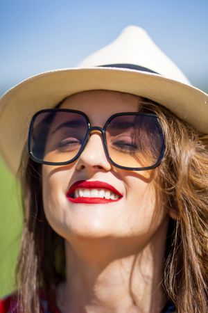 Cheerful woman in sunglasses looking at camera on sunny day