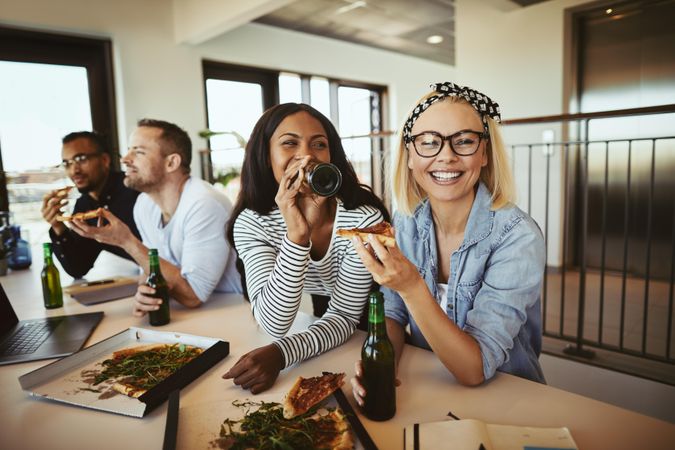 Two young businesswomen enjoying pizza lunch at work