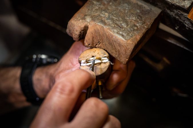 Jeweler hands setting a diamond into a ring with a burin in a jewelry workshop. Goldsmith working and creating a gold jewel.