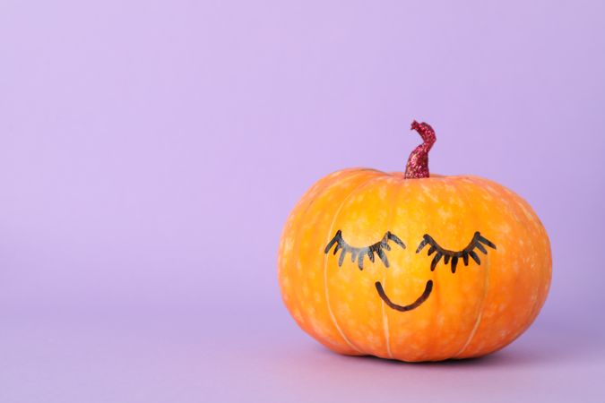 Pumpkin with smile on violet background, space for text