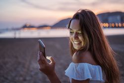 Cheerful young woman using smartphone on resort
