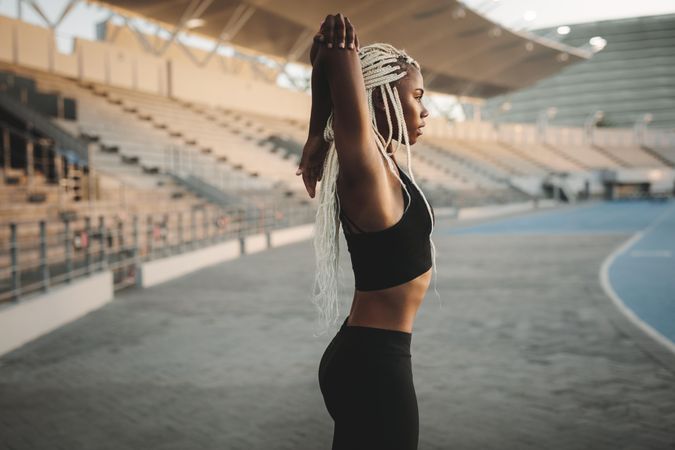 Woman athlete doing exercise in a track and field stadium