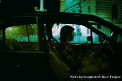 Side view of young man sitting in a car at night 5QYKV5