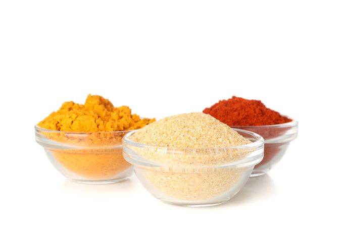 Three glass bowls of colorful spices
