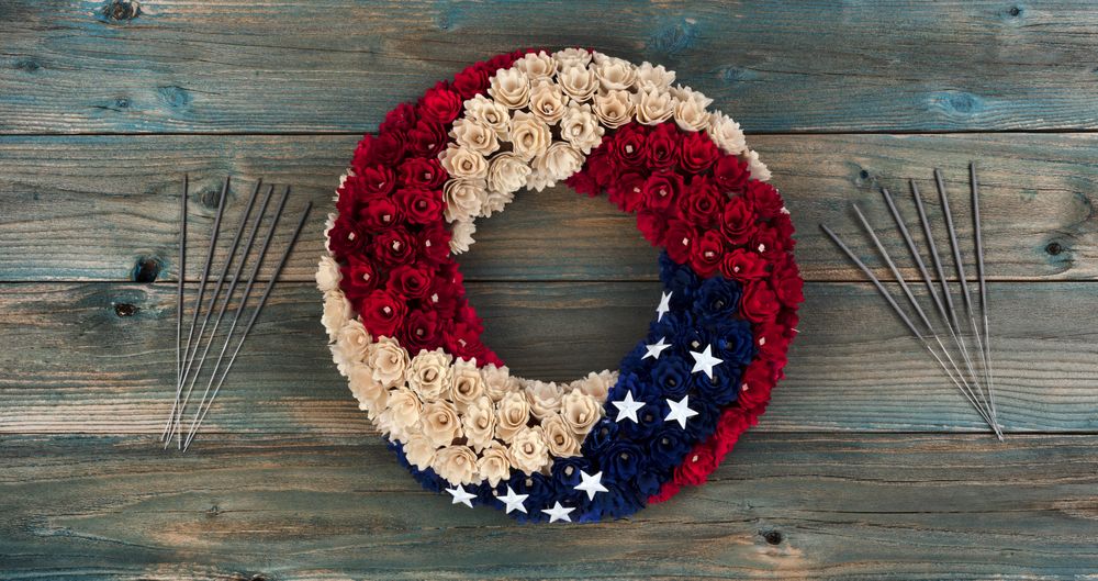 Wreath with US national colors of red, and blue with stars plus sparklers on faded blue wooden planks for happy memorial or Independence Day background
