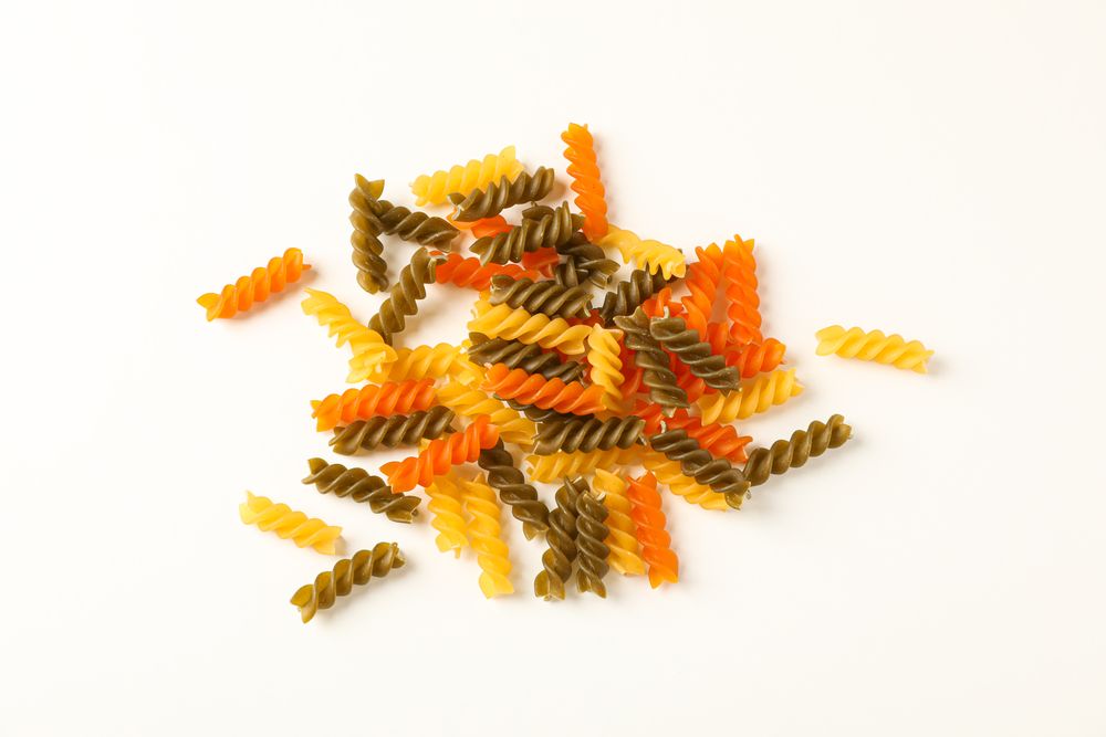 Color pasta on blank background, space for text. Dry uncooked whole pasta