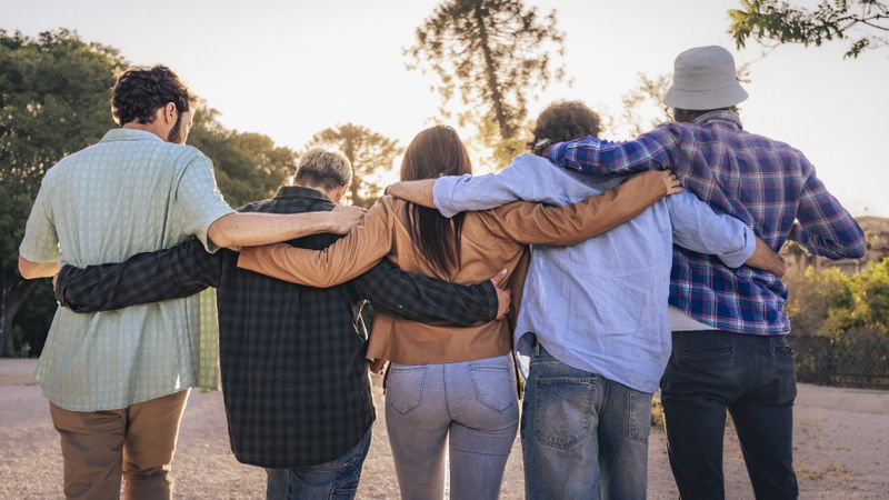 Group of friends smiling outdoors wearing sunglasses and casual shirts