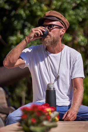 Bearded man drinking tea from thermos lid