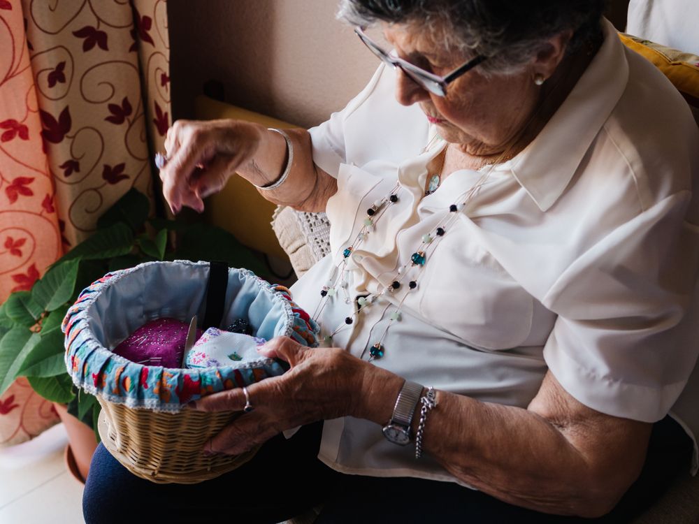 Older female taking knitting tools at home
