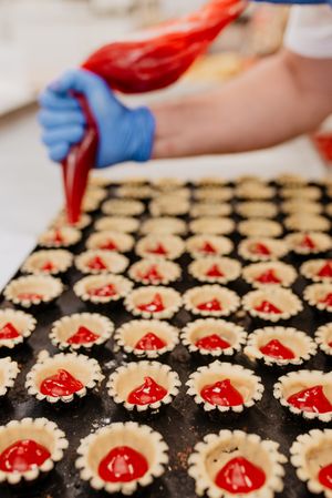 Crop baker filling pastry cases with jelly