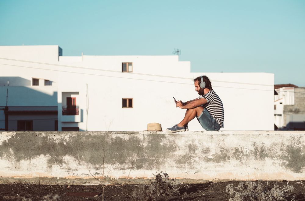 Young male sitting with smartphone and headphones