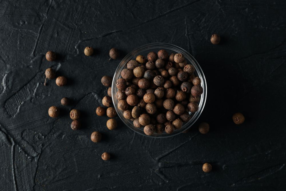 Top view of glass bowl with peppercorns on dark background