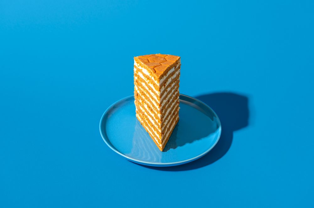 Honey layered cake slice, russian recipe, isolated on a blue background