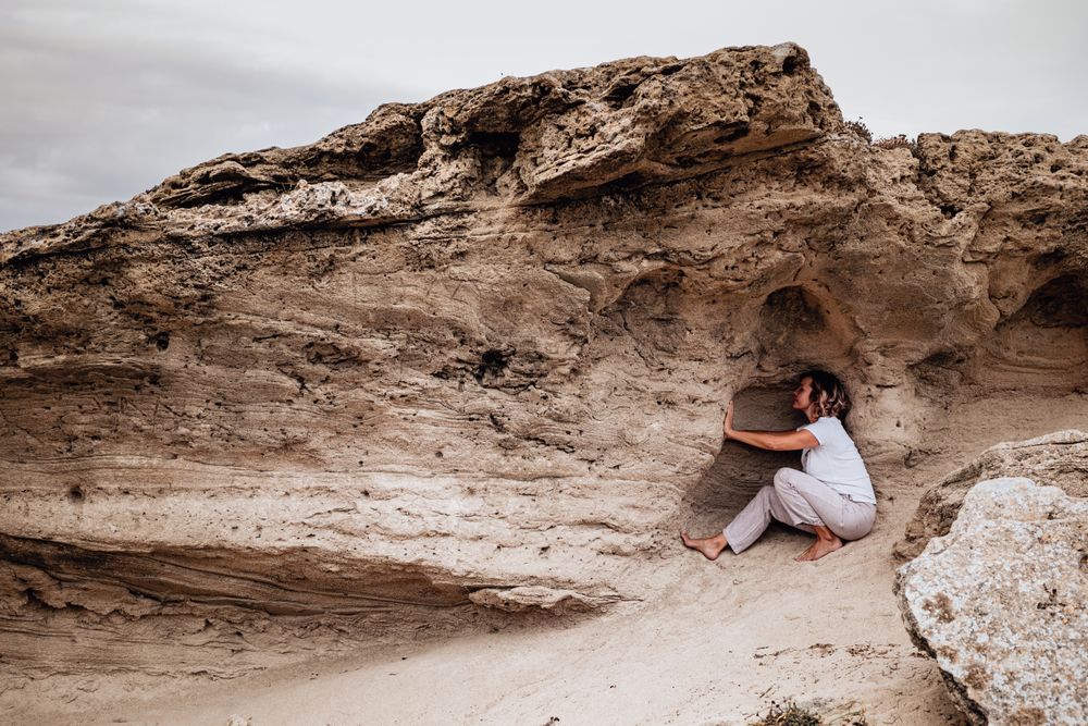 Barefoot woman meditating in rock cavity