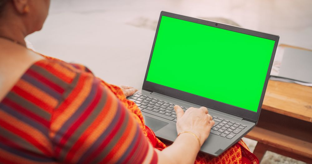 Over-the-Shoulder View of Mature Indian Woman Using Laptop with Green Screen