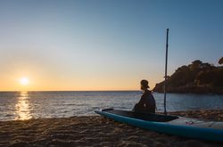 Man practicing paddle surfing with neoprene in a sunrise