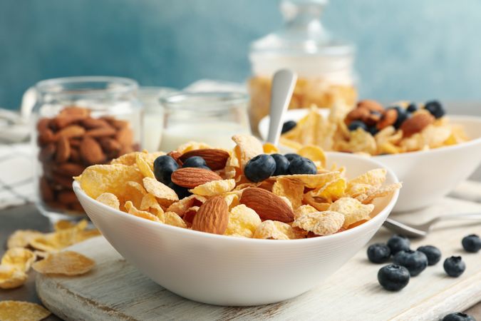 Concept of breakfast with muesli, berry, nut and milk on gray table