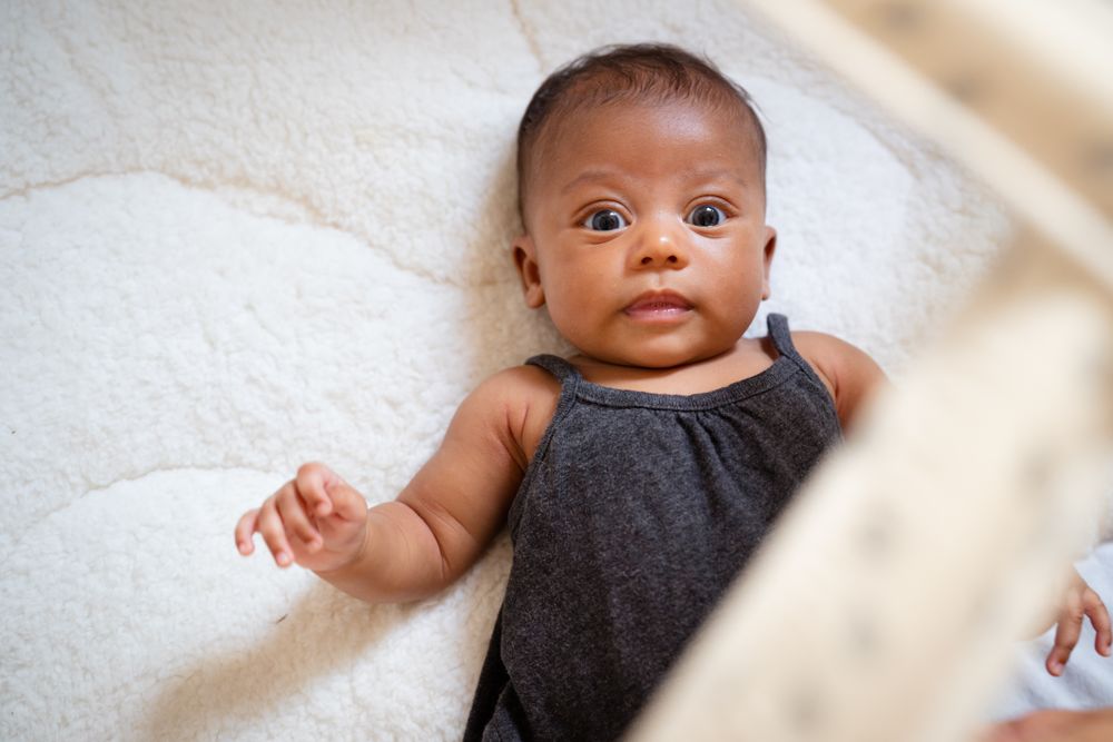 Cute baby girl with huge eyes lying on her back
