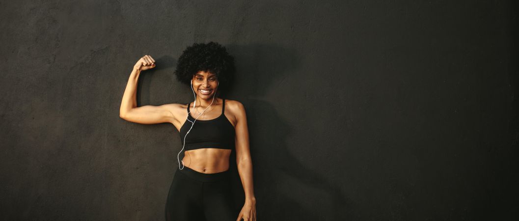 Young fitness woman flexing muscles and smiling