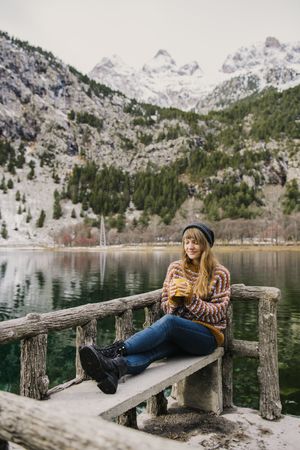 Woman on seat near wonderful lake between hills in snow