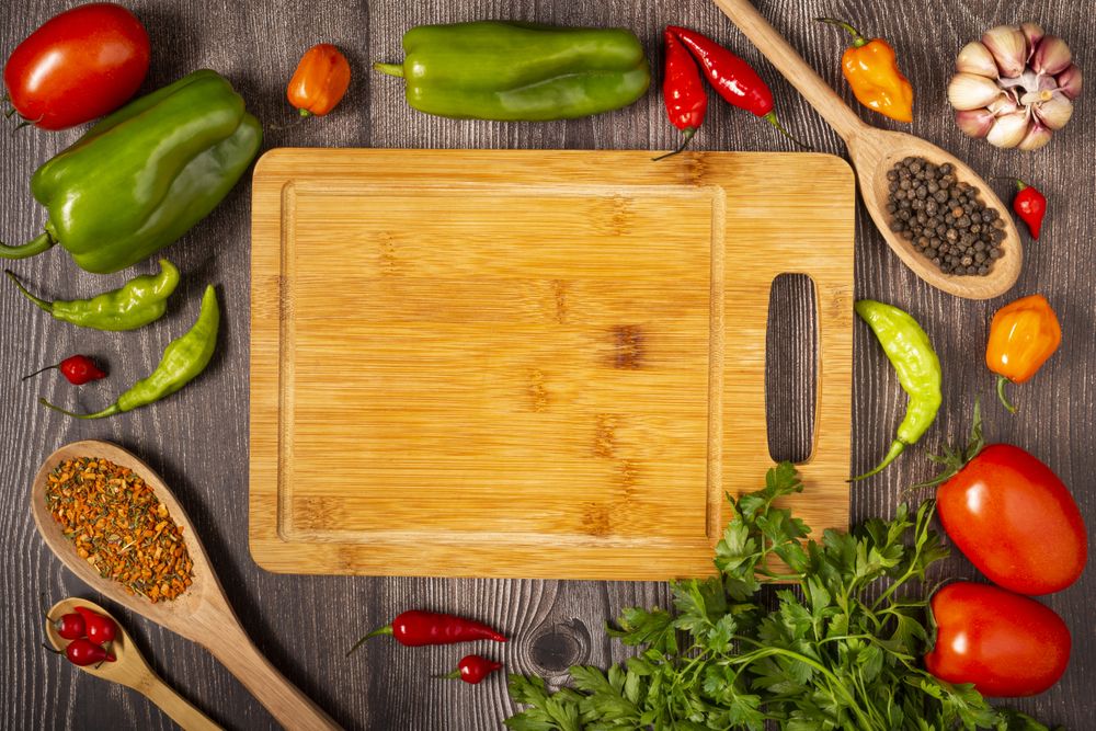 Empty cutting  board on the table with Ingredients for cooking. Tomatoes, various peppers, garlic and green peppers.